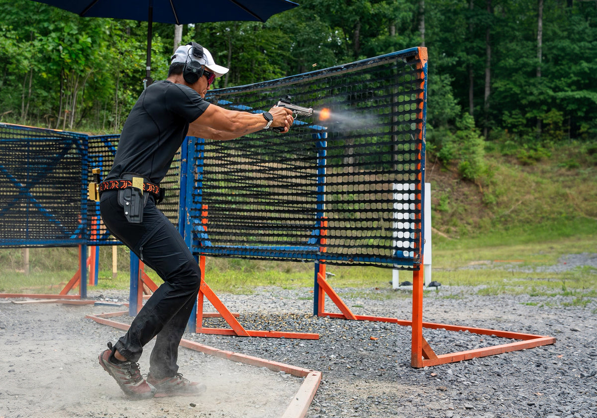 USPSA competition shooter with firearm shooting paper target